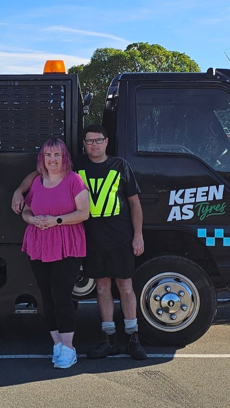 Two people standing next to a black van with 'Keen As Tyres' branding.
